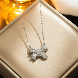 Elegant silver bow pendant necklace with crystals on a beige jewelry display box