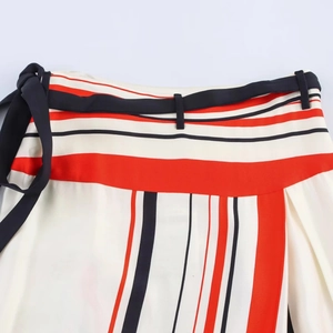 Detail of striped skirt waist with black ribbon tie and bow on silky cream fabric