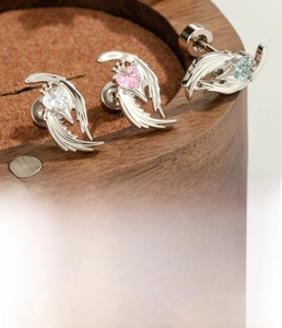 Macro shot of silver wing cartilage earring with heart-shaped zircon and titanium steel post