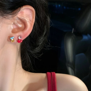 Close-up of asymmetrical zircon letter earrings with colorful enamel details on ear.