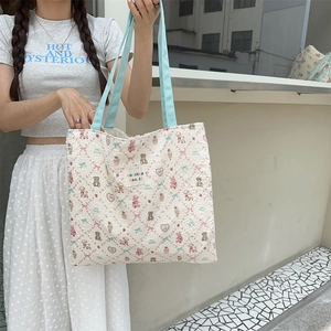 Detail of floral embossed canvas tote bag featuring cute animal prints and woven handles