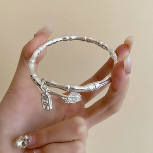 Detail of silver bamboo joint bangle with lotus pendant and peace tag on wrist