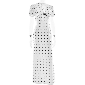 Detailed view of white polka dot V-neck dress with black bow on a transparent mannequin