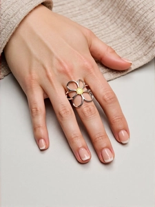 Close-up of a hollow silver flower ring with a golden center on a hand with French manicure
