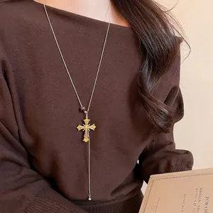 Retro gold long necklace with diamond-set cross pendant and tassel on knitwear
