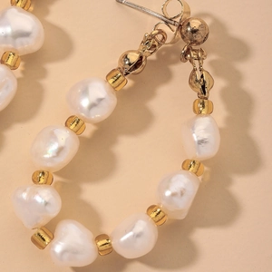 Macro view of French vintage earrings with baroque pearls and gold beads on beige fabric