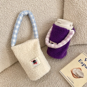 Detail of plush lamb wool cup carrier bags with checkered handles and cartoon cat patch