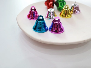 Close-up of colorful 26mm matte vacuum plated metal bells in a beige ceramic tray