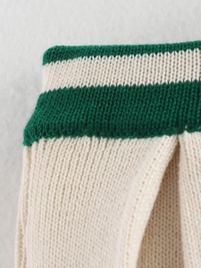 Detailed close-up of cream knit fabric with green horizontal stripes and fine texture