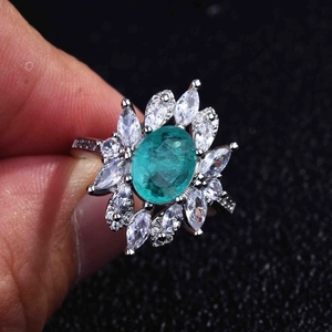 Detail of flower cluster ring with oval green gemstone and marquise zircons