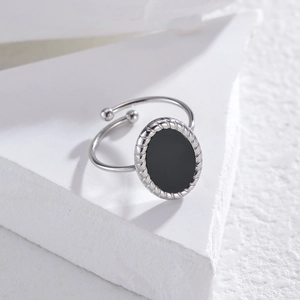 Détail d'une bague ajustable argentée avec incrustation noire et texture de corde torsadée