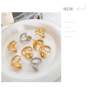 Detail of assorted gold and silver fluid wavy rings on a white ceramic plate