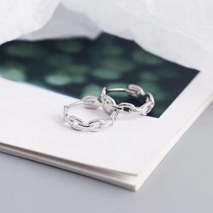Detail view of silver chain drop earrings resting on a book with soft lighting