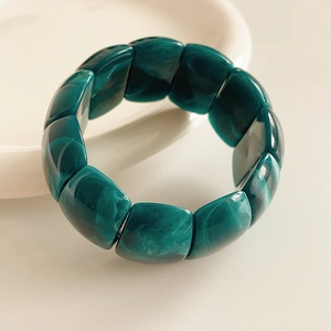 Macro detail of dark green marble-textured resin blocks on a stylish geometric bracelet