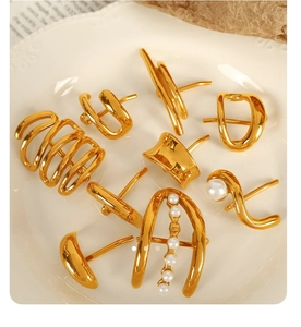 Detailed close-up of golden geometric earrings with pearls on white ceramic plate
