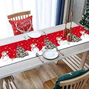 Detailed view of red Christmas table runner with snowman and tree patterns on wood table