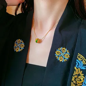 Collana placcata oro 18K con ciondolo rotondo traforato e smalto verde su modella