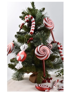 Detail of red and white candy cane and swirl lollipop ornaments on a Christmas tree
