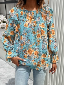 Detail of teal floral blouse featuring orange flowers, ruffled sleeves and smocked chest