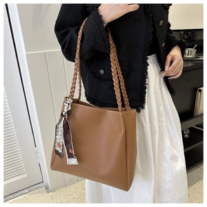 Detail of a brown leather tote bag featuring white stitching and a geometric silk scarf
