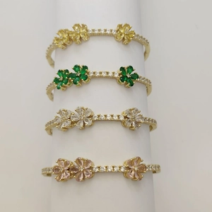 Detailed stack of clover charm bracelets with yellow, green, white, and pink zircons