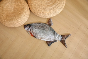 Detailed realistic fish plush showing lifelike scales and texture on a light wood floor
