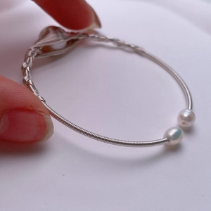 Detailed close-up of handmade flexible silver wire-wrapped pearl bracelet with dual pearls