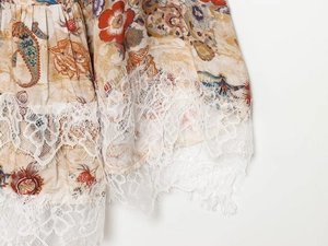 Detailed close-up of floral paisley pattern fabric with delicate white lace hem trim