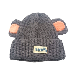 Détail du bonnet en maille gris foncé avec oreilles d'ours orange et étiquette Lucky