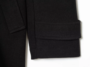 Close-up of black woolen coat cuff showing premium fabric texture and precise stitching