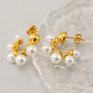 French retro gold C-shaped earrings with freshwater pearls on a textured background