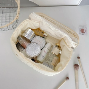Top view of open cream quilted cosmetic bag showing large storage capacity for makeup