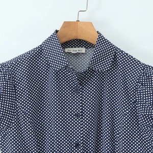 Navy blue polka dot blouse with puff sleeves and front buttons on a wooden hanger