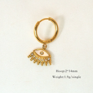 Macro shot of gold hoop earring with white enamel evil eye charm and clear zircon stones