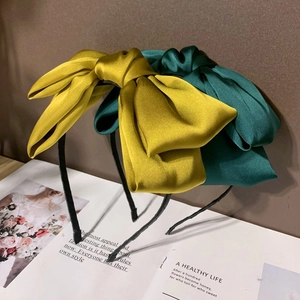 Détail de serre-têtes en soie à nœud jaune et vert posés sur un magazine