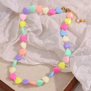 Close-up of colorful acrylic heart beads and pearls on a gold chain necklace