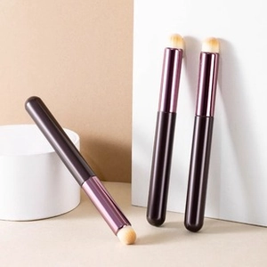 Detail of three professional makeup brushes with purple gradient handles on white props