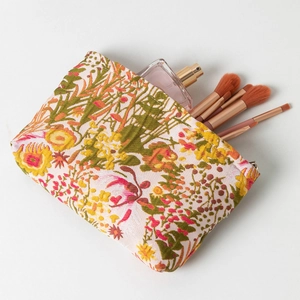 Detail of floral makeup bag with perfume and brushes inside the storage compartment