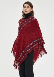 Close-up of red knit poncho with colorful zigzag patterns and tassel hem fringe detail