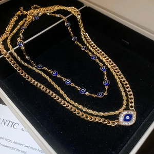 Close-up of golden evil eye layered necklaces with blue enamel and sparkling crystals