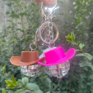 Detailansicht von Disco-Kugel-Schlüsselanhängern mit rosa und braunen Cowboyhüten