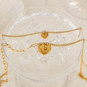 Close-up of golden heart pendants with textures on glass tray with ice cubes