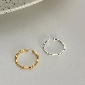 Detailed view of gold and silver bamboo texture adjustable open rings on a ceramic background