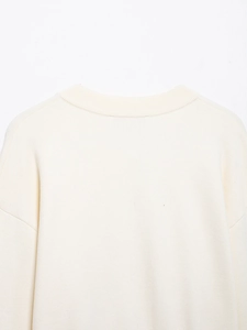 Close-up of ivory knit cardigan showing ribbed crew neck and soft textured knit details