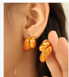 Detail view of stylish gold-toned C-shaped heart earrings worn by a female model