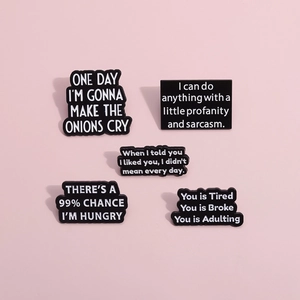 Detailed view of five black enamel pins with humorous slogans on a pink background