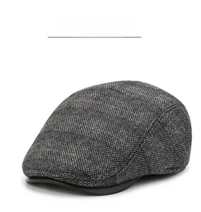 Details von grauem Fischgrätmuster und Lederkrempe an einer Vintage-Schiebermütze