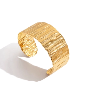 Polished gold wide stainless steel cuff bracelet featuring a textured hammer finish