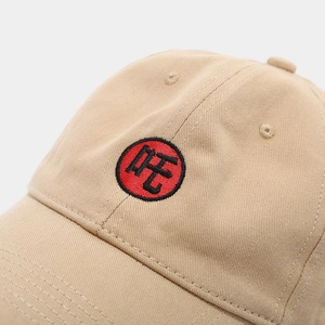 Close-up of khaki cotton twill baseball cap featuring detailed red circle embroidery