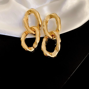Détail des boucles d'oreilles doubles boucles dorées irrégulières au style métal